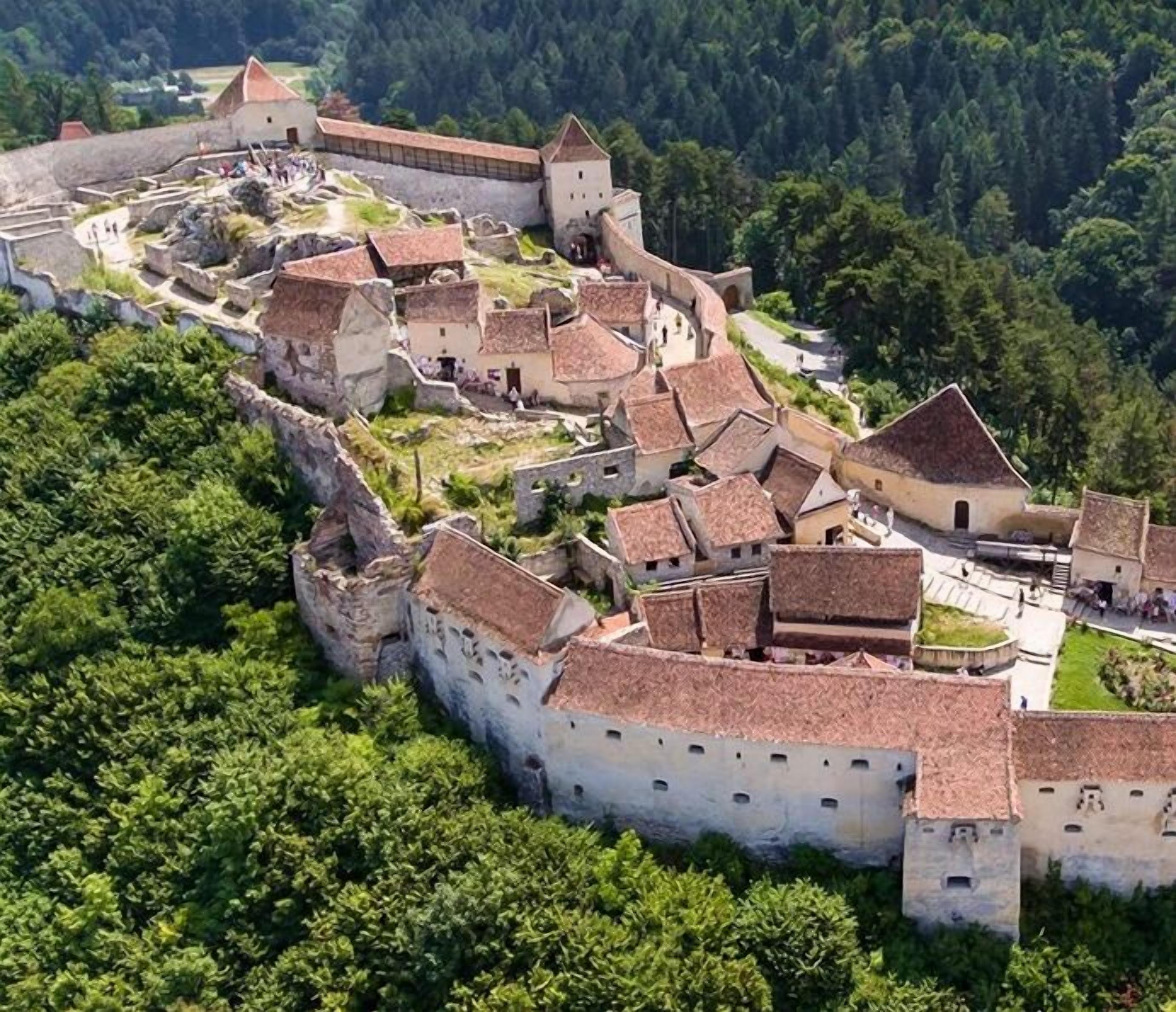 An aerial view of a historic walled town with medieval architecture, including a prominent castle and surrounding buildings.