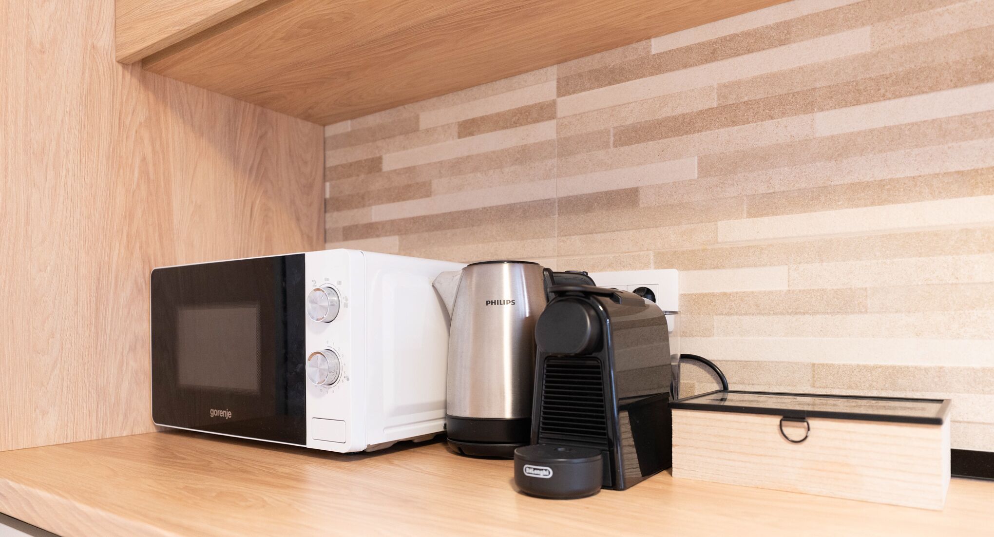 Une cuisine équipée d’un four à micro-ondes, d’une machine à café et d’un grille-pain, le tout posé sur un plan de travail en bois.