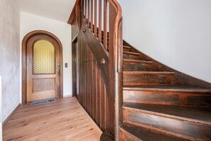 Una escalera de madera que conduce a una habitación con una puerta de madera y un panel de vidrio.