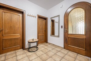 Un pasillo con puertas de madera, una pequeña mesa redonda con un florero y un espejo en la pared.
