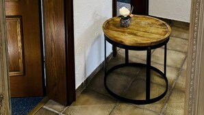 Ein Flur mit einer Holztür, einem runden Tisch mit einer Vase und einem an der Wand befestigten Haken.