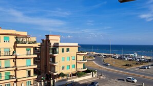 A coastal building with multiple balconies overlooking the sea, a parking area with cars, and a clear view of the ocean. - Sea Vibes Rome - Relax by the sea and reach Rome in minutes (Lido di Ostia)