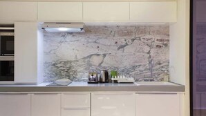 A modern kitchen with white cabinetry, a marble backsplash, and a built-in oven. - A Modern and Unique Loft - Center of Paris (Paris)