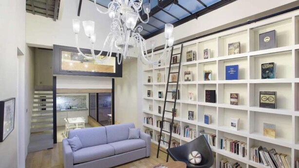 A modern living room with a grey sofa, a wooden coffee table, and a bookshelf filled with books and decorative items. - A Modern and Unique Loft - Center of Paris (Paris)