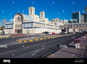 A street with a mosque featuring a large dome and minarets, surrounded by modern buildings. - Al Dar Hotel (Sharjah)