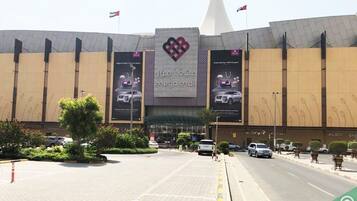 A large, modern shopping mall with a prominent logo and multiple flags.