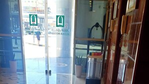 A hotel lobby with a shiny tiled floor, a reception desk, and a glass door leading outside. - Al Dar Hotel (Sharjah)