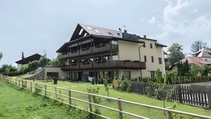 Un immeuble à plusieurs étages doté de balcons, d’un toit en pente et d’une cour clôturée.