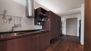 Une cuisine moderne dotée d’un plan de travail en bois, d’un évier en acier inoxydable et d’ustensiles de cuisine suspendus.