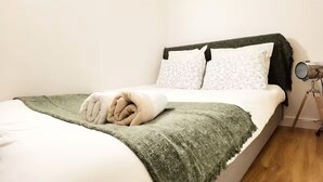 A neatly made bed with a green blanket, white pillows, and a white duvet. - Stylish Marais Duplex near Pompidou & Metro (Paris)