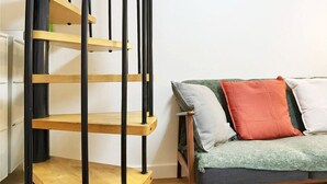 A spiral staircase with wooden steps and black metal railings. - Stylish Marais Duplex near Pompidou & Metro (Paris)