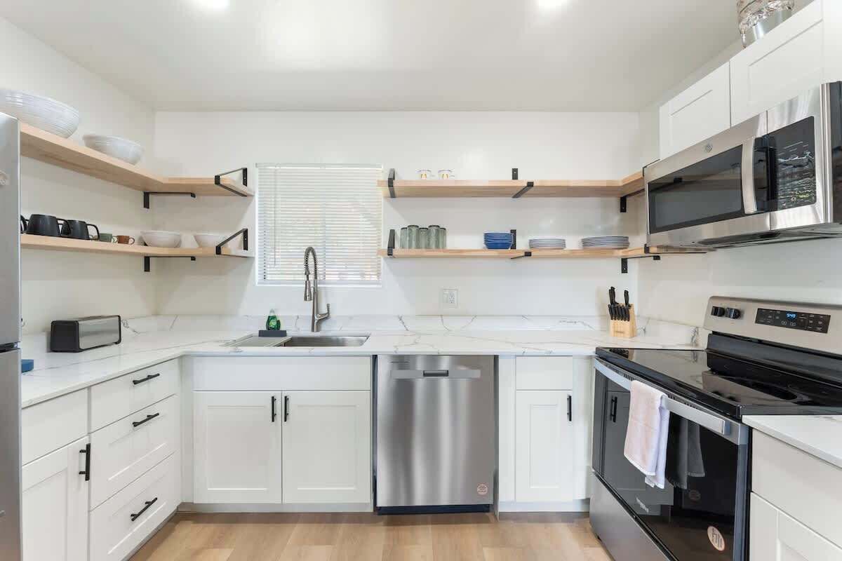 Een moderne keuken met witte kasten, een RVS vaatwasser, een zwarte oven en een magnetron.