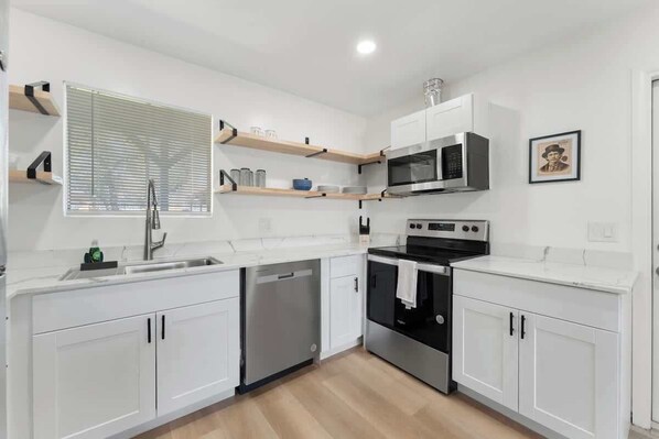 A modern kitchen with white cabinetry, a built-in oven, a microwave, and a dishwasher.