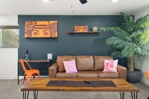 A modern living room with a leather sofa, a wooden coffee table, and a large potted plant.