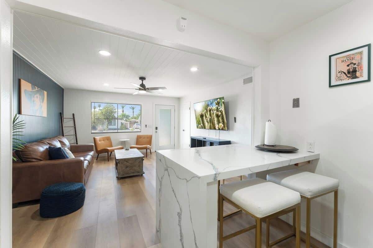 A modern living room with a marble island, leather sofa, and a dining area.