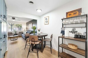 A modern living room with a dining area, a coffee station, and a view of the outdoors. - The Rose 4 Apts|Pool|Gazebo|CentralPhx|Sleeps20 (Phoenix)
