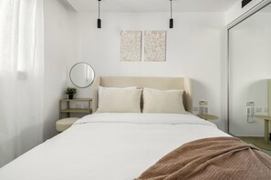 A modern hotel room with a large bed, a bedside table with a plant, a round mirror, and two wall-mounted artwork pieces. - Red Canyon Spa Bright Stay by Sea N Rent (Eilat)
