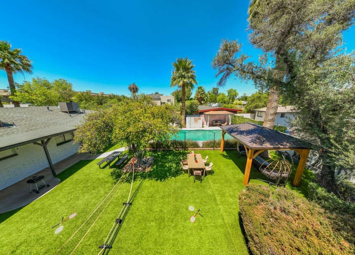 Ein Garten mit Esstisch, Grill und einer Pergola.