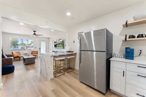 A modern kitchen with a stainless steel refrigerator, wooden bar stools, and a white countertop. - Central Phoenix Apt w/ Pool & Gazebo (Phoenix)