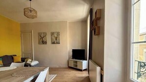 A modern kitchen with a wooden table, white chairs, and a built-in TV. - Appartement Confort Laval Centre ! (Laval)
