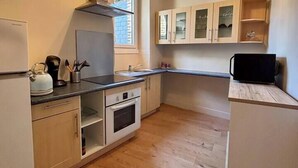 A compact kitchen with wooden cabinets, a built-in oven, and a window providing natural light. - Appartement Confort Laval Centre ! (Laval)