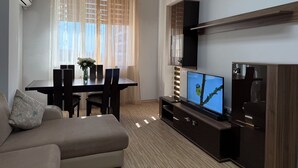 Una sala de estar moderna con un sofá, una mesa de comedor con sillas, un televisor y un aparador de madera.
