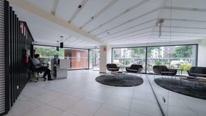 A modern reception area with a counter, seating, and large windows.