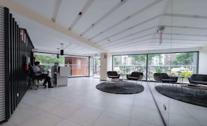 A modern reception area with a counter, seating, and large windows. - w* | Exceptional 1BR w/ Balcony  in San Isidro (San Isidro)