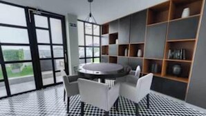 A modern room with a round table, chairs, a bookshelf, and large windows.