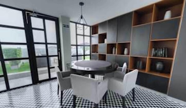 A modern room with a round table, chairs, a bookshelf, and large windows.