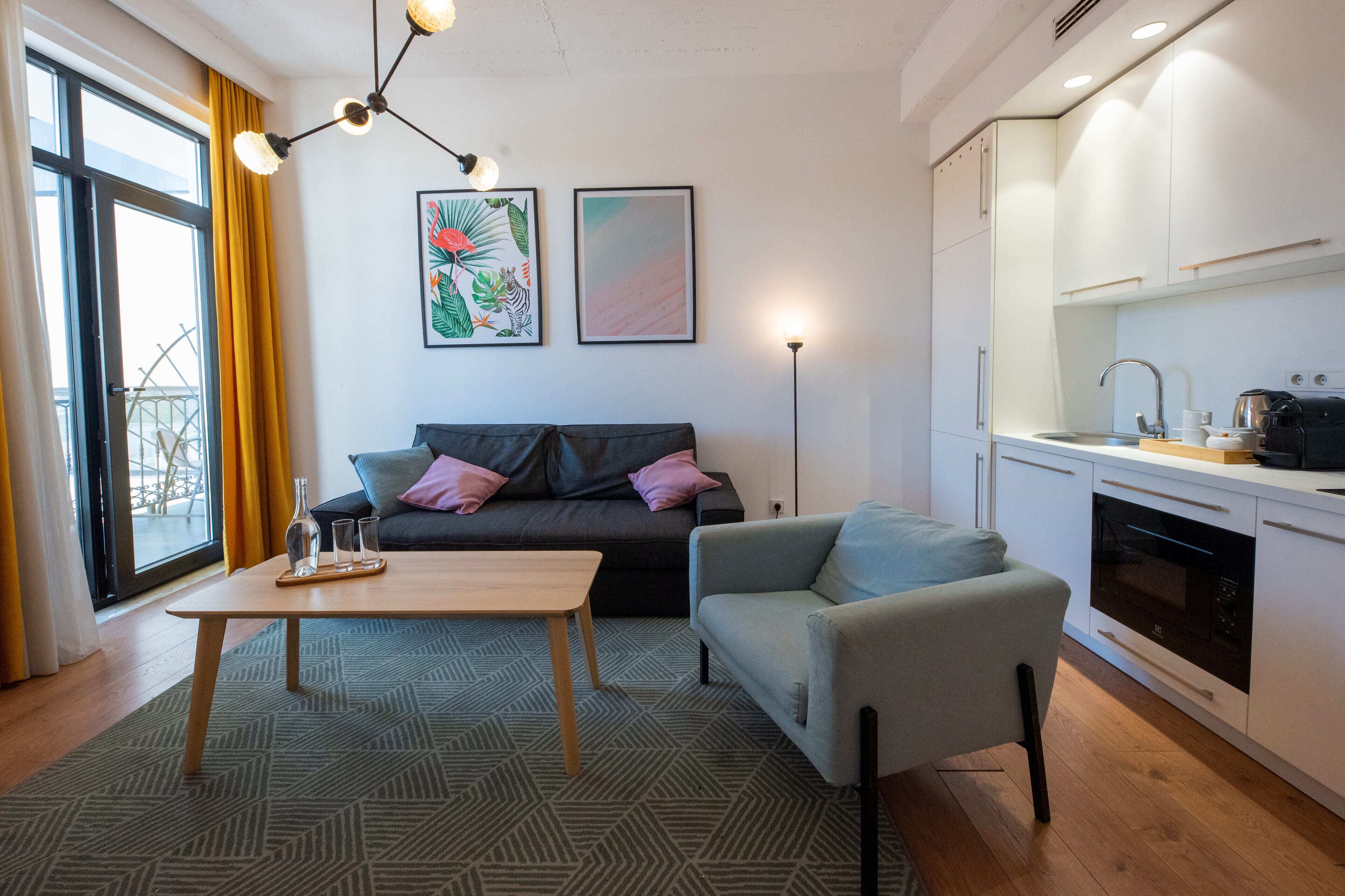 A modern living room with a sofa, a coffee table, and a dining area with a kitchen.