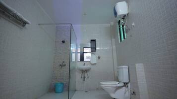 A compact bathroom with a glass shower enclosure, a white sink, and a toilet.