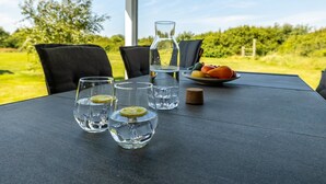 Une table avec quatre verres d’eau, une bouteille et une assiette de fruits.