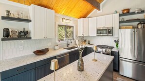 A modern kitchen with white cabinetry, a granite countertop, stainless steel appliances, and a decorative vase.