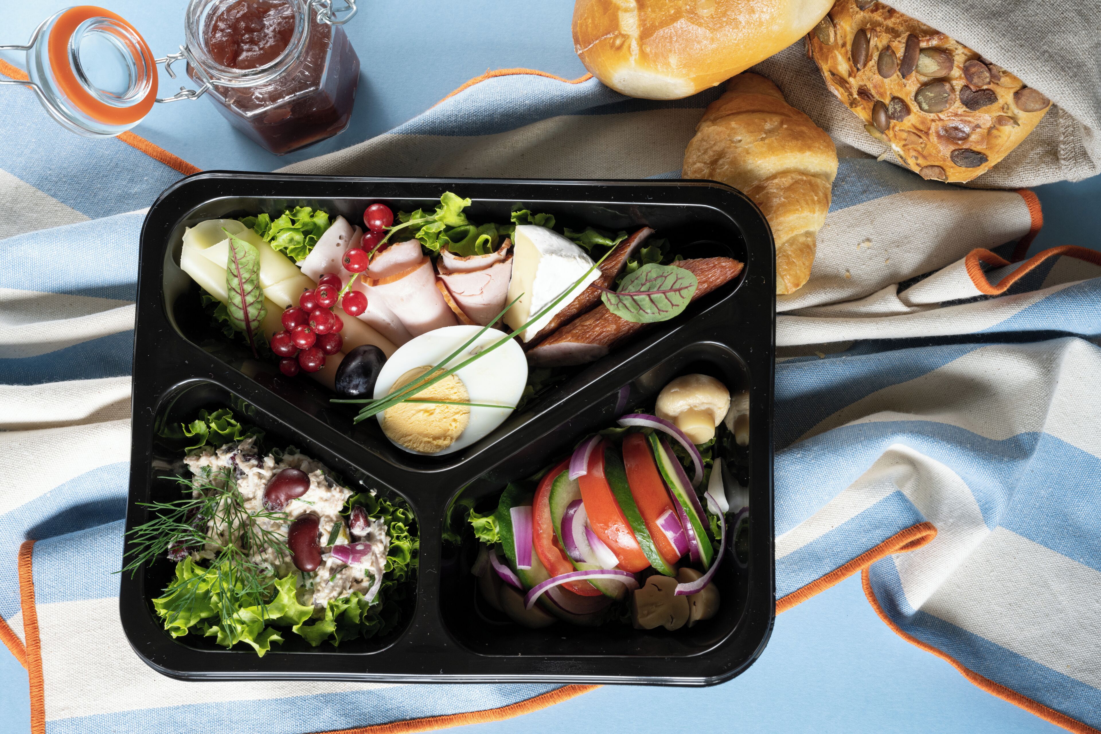 A meal tray with various food items including vegetables, cheese, and meat.