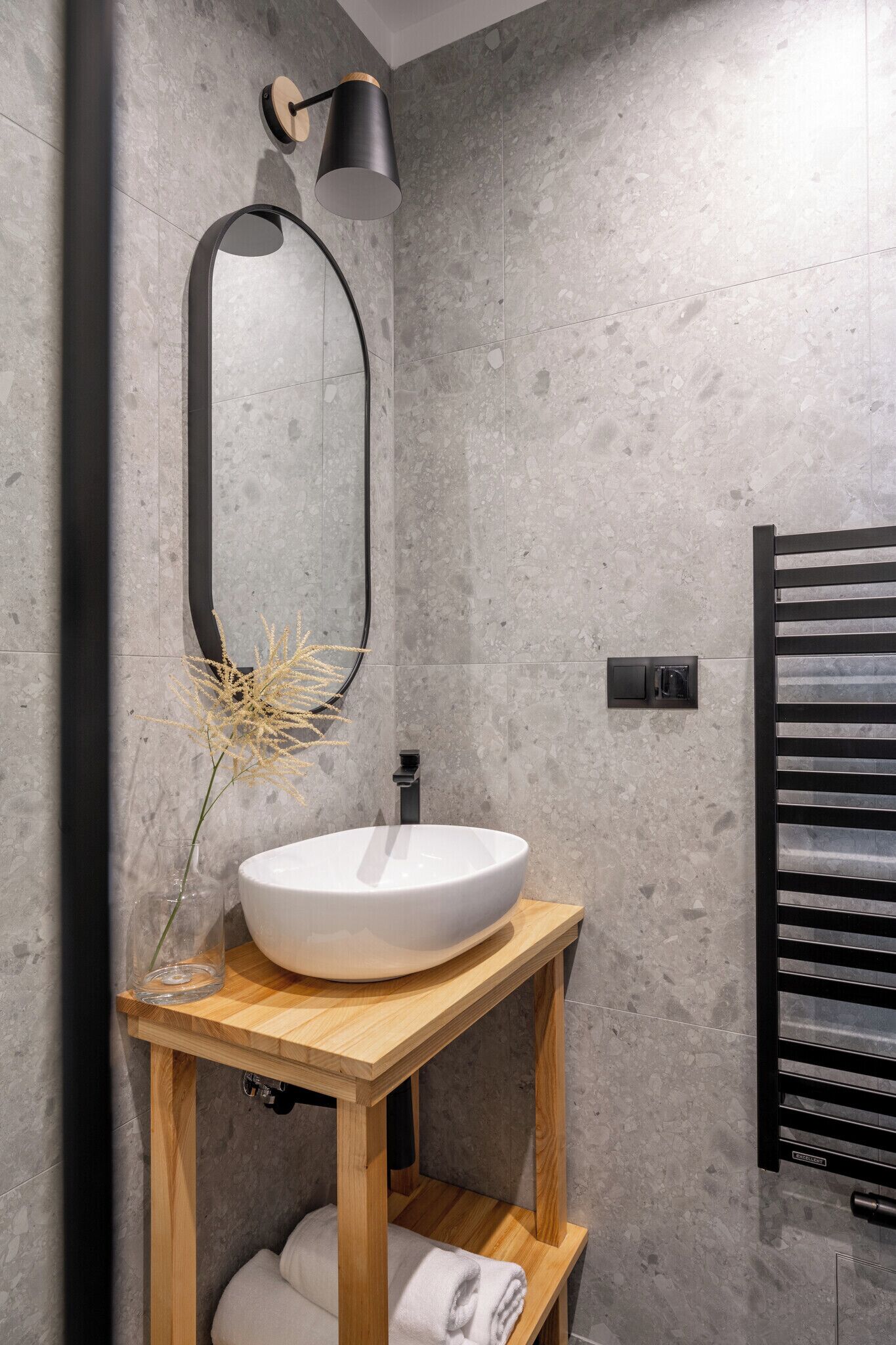 A modern bathroom with a freestanding wooden vanity, a white sink, a mirror, and a towel rack.