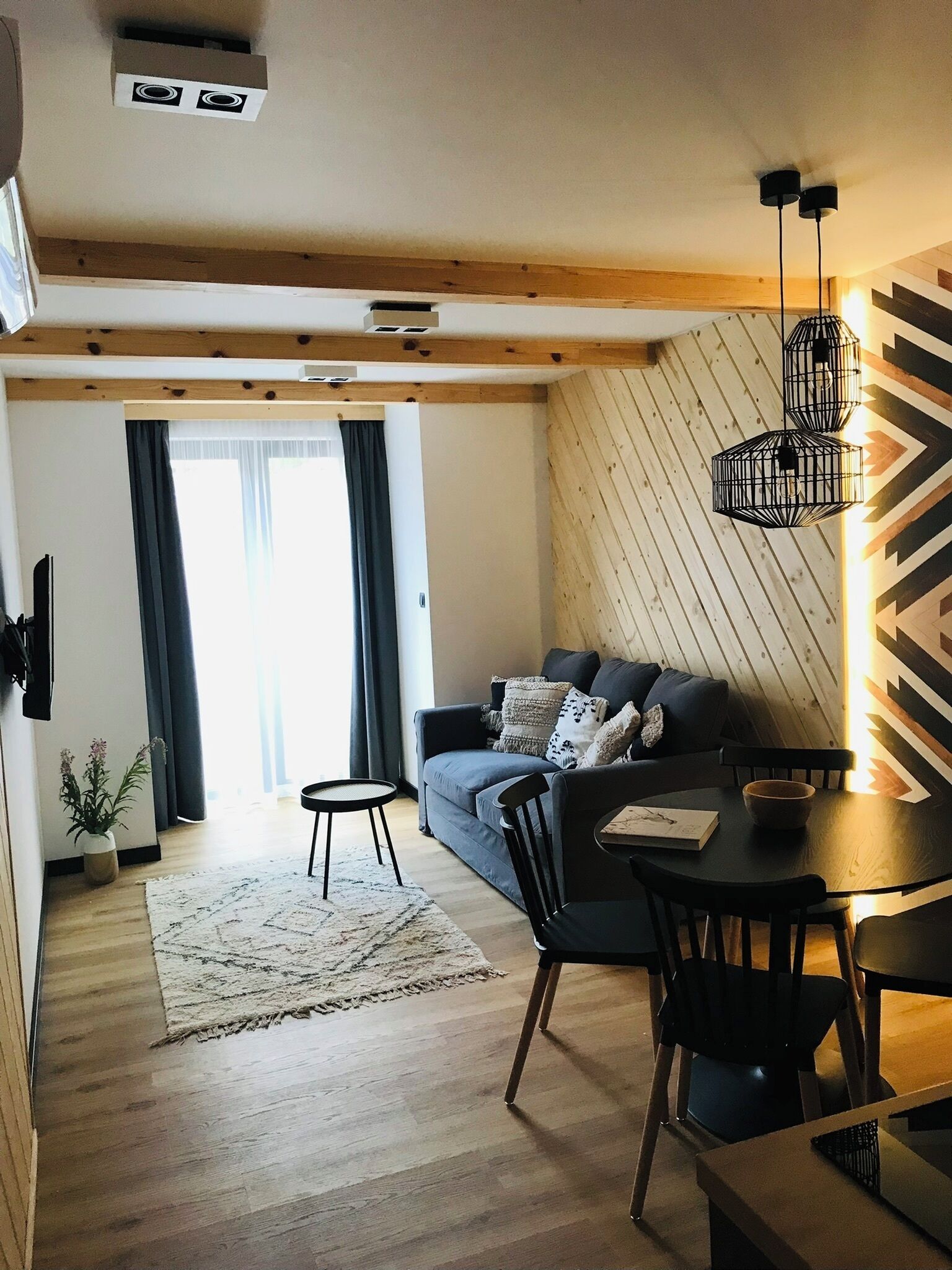 A modern living room with a sofa, dining table, chairs, and a small rug.