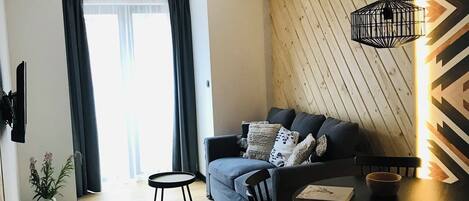 A modern living room with a sofa, dining table, chairs, and a small rug.