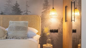 Un dormitorio con cama, una mesita de noche con un florero y un mural en la pared con un bosque.