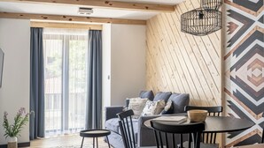 Un salon moderne avec un canapé, des fauteuils, une petite table et un mur décoré d’un motif.