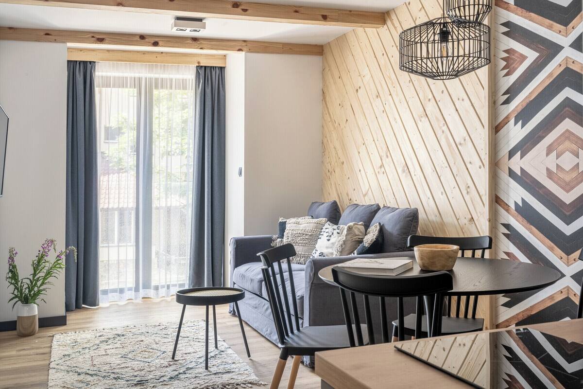 Ein modernes Wohnzimmer mit einer Couch, Sesseln, einem kleinen Tisch und einer Wand mit Muster.