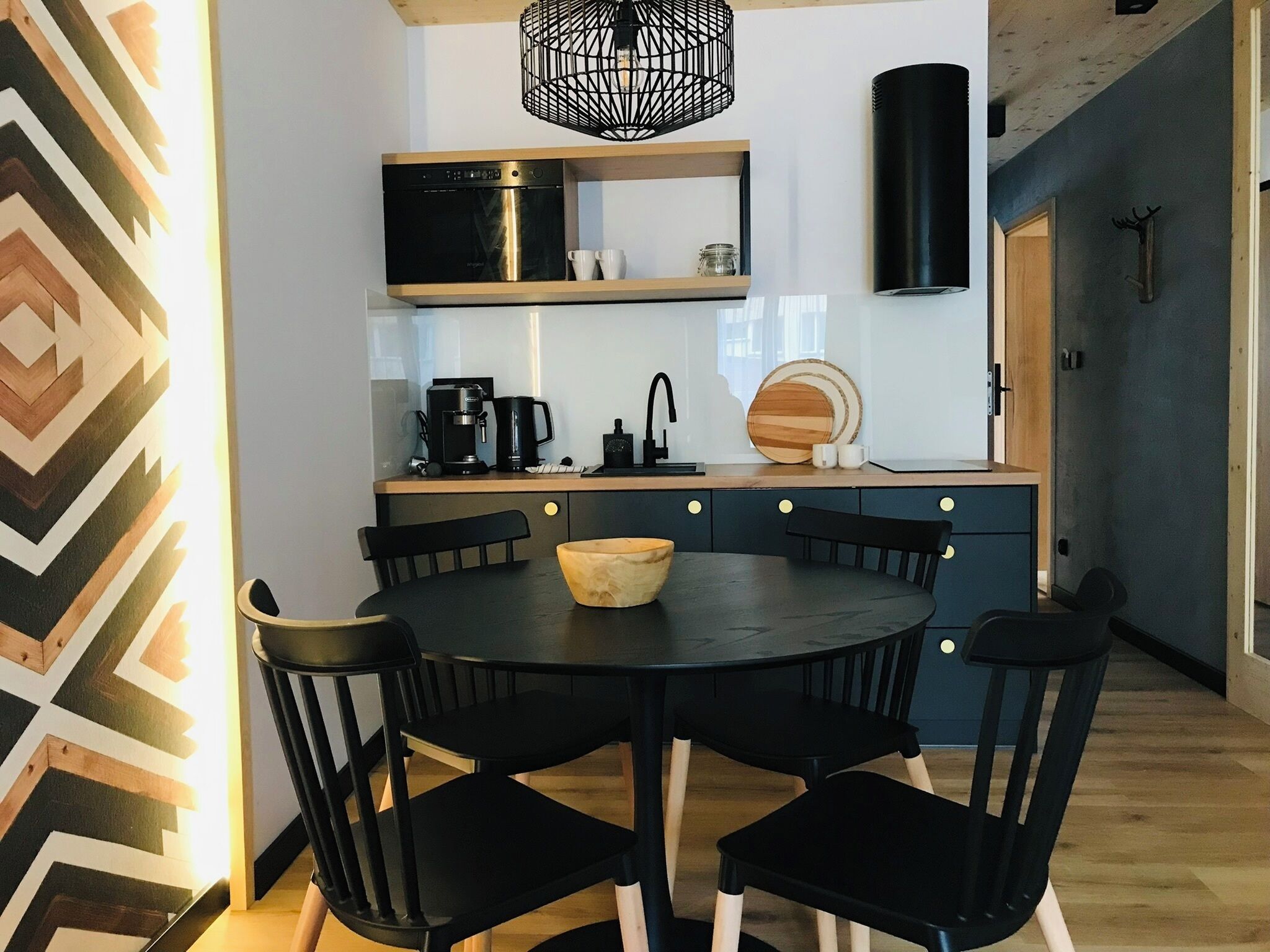 Una cocina moderna con una mesa redonda, sillas negras y una cafetera.