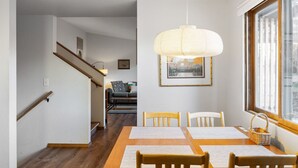 A dining area with a wooden table, chairs, and a hanging light fixture.