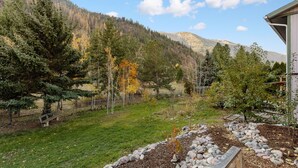 A mountainous landscape with a grassy area, trees, and a wooden bench.
