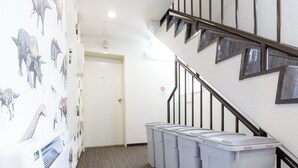 A hallway with a carpeted floor, a staircase with a metal railing, and a door with a no-smoking sign. - Tabist JKN Twin Hotel (Asahikawa)
