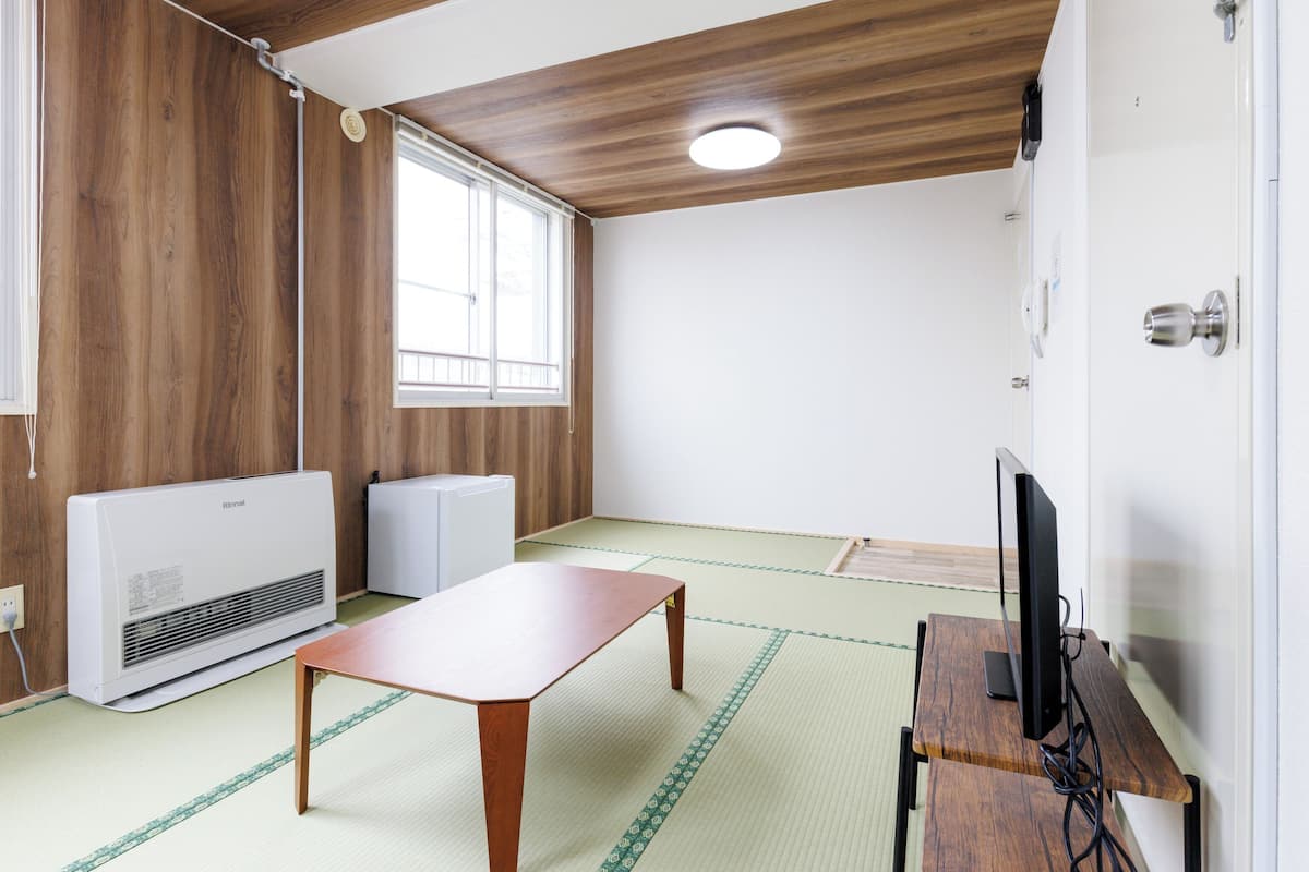 Une pièce avec un plafond en bois, une grande fenêtre, une table, un téléviseur et un radiateur.