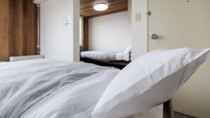 A bedroom with a wooden ceiling, a bed with white bedding, and a door with a poster. - Tabist JKN Twin Hotel (Asahikawa)
