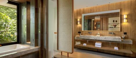 Une salle de bain moderne avec un grand miroir, deux lavabos et un banc.