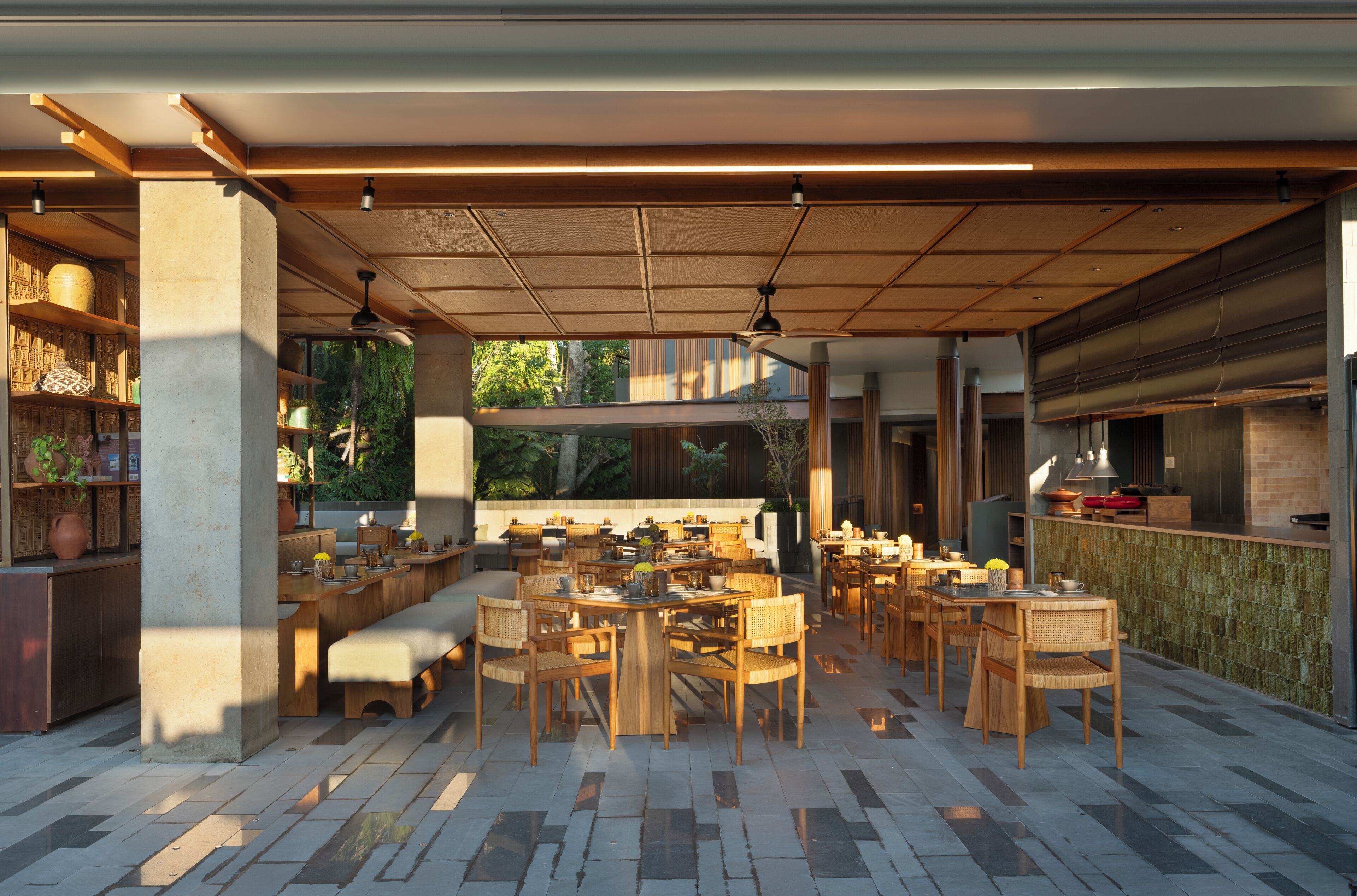 An outdoor dining area with multiple tables and chairs, a bar, and a seating area with a bench.