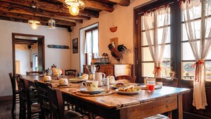 A rustic dining room with a wooden table set for a meal, surrounded by chairs. - Agriturismo Le Noci (Tarzo)